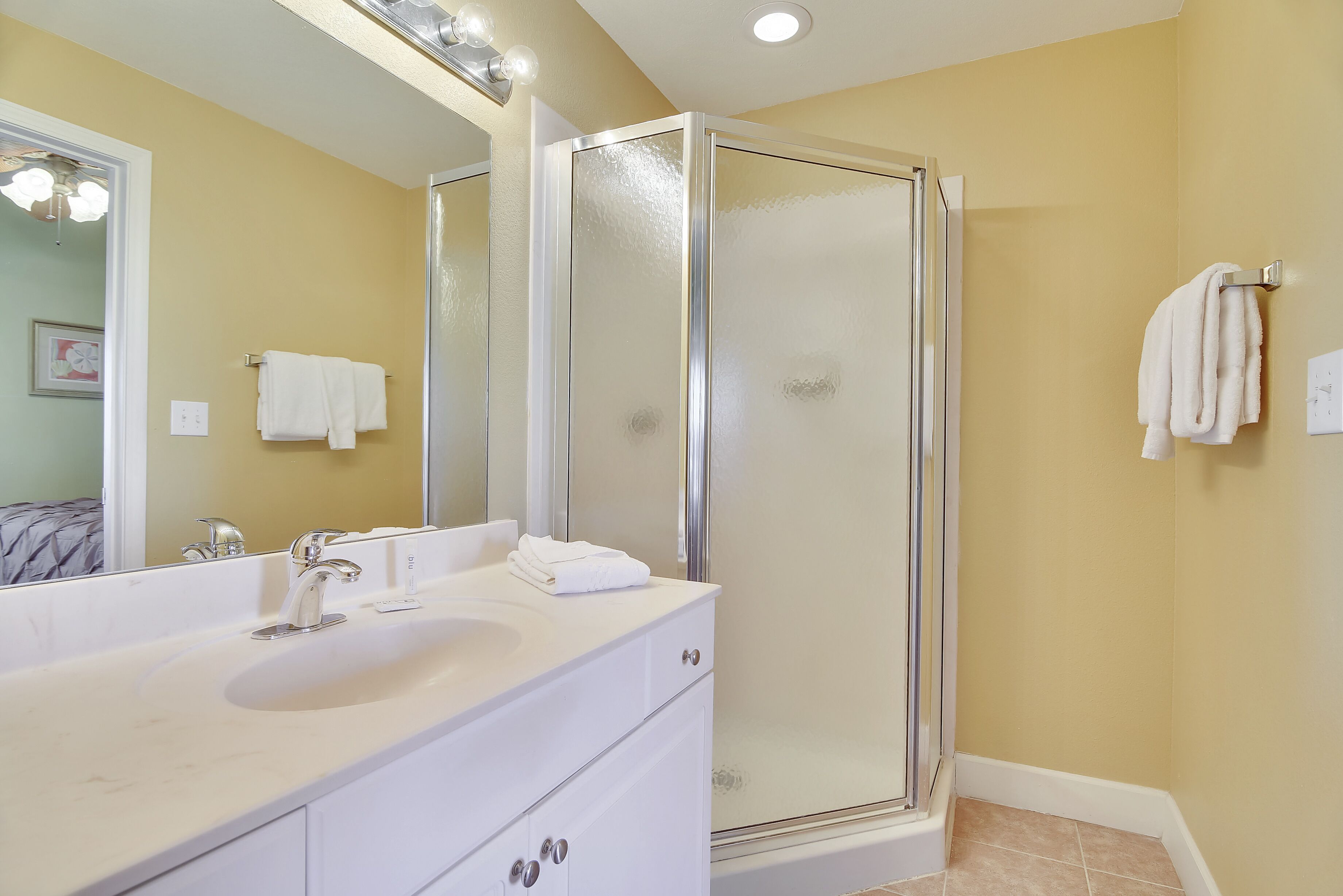 A bathroom with a white vanity, a glass-enclosed shower, and a large mirror.