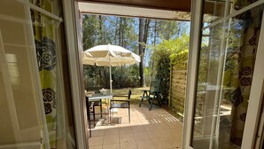 An open sliding glass door leading to a patio area with a table, chairs, and a large umbrella.