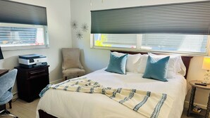 Ein Hotelzimmer mit einem Bett, einem Sessel, einem Schreibtisch mit Drucker und einer Lampe.