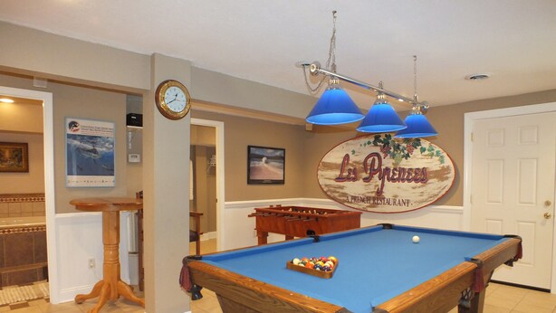 A pool table with a blue felt surface, a clock on the wall, and a sign for "Les Pyramides" restaurant. - BEACH GETAWAY W/ JACUZZI TUB & GAME ROOM CENTRALLY LOCATED SPACIOUS ROOMS (Kill Devil Hills)