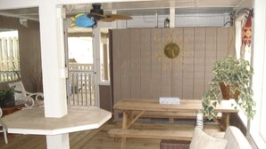 A wooden deck with a table and benches, a white cushioned bench, a wicker basket, and a hanging plant. - BEACH GETAWAY W/ JACUZZI TUB & GAME ROOM CENTRALLY LOCATED SPACIOUS ROOMS (Kill Devil Hills)