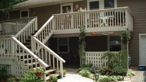 A two-story house with a front porch, a staircase, and a small garden area. - BEACH GETAWAY W/ JACUZZI TUB & GAME ROOM CENTRALLY LOCATED SPACIOUS ROOMS (Kill Devil Hills)