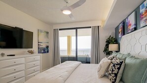 Une chambre moderne avec un lit, une télévision, un balcon avec des rideaux et des œuvres d’art accrochées au mur.