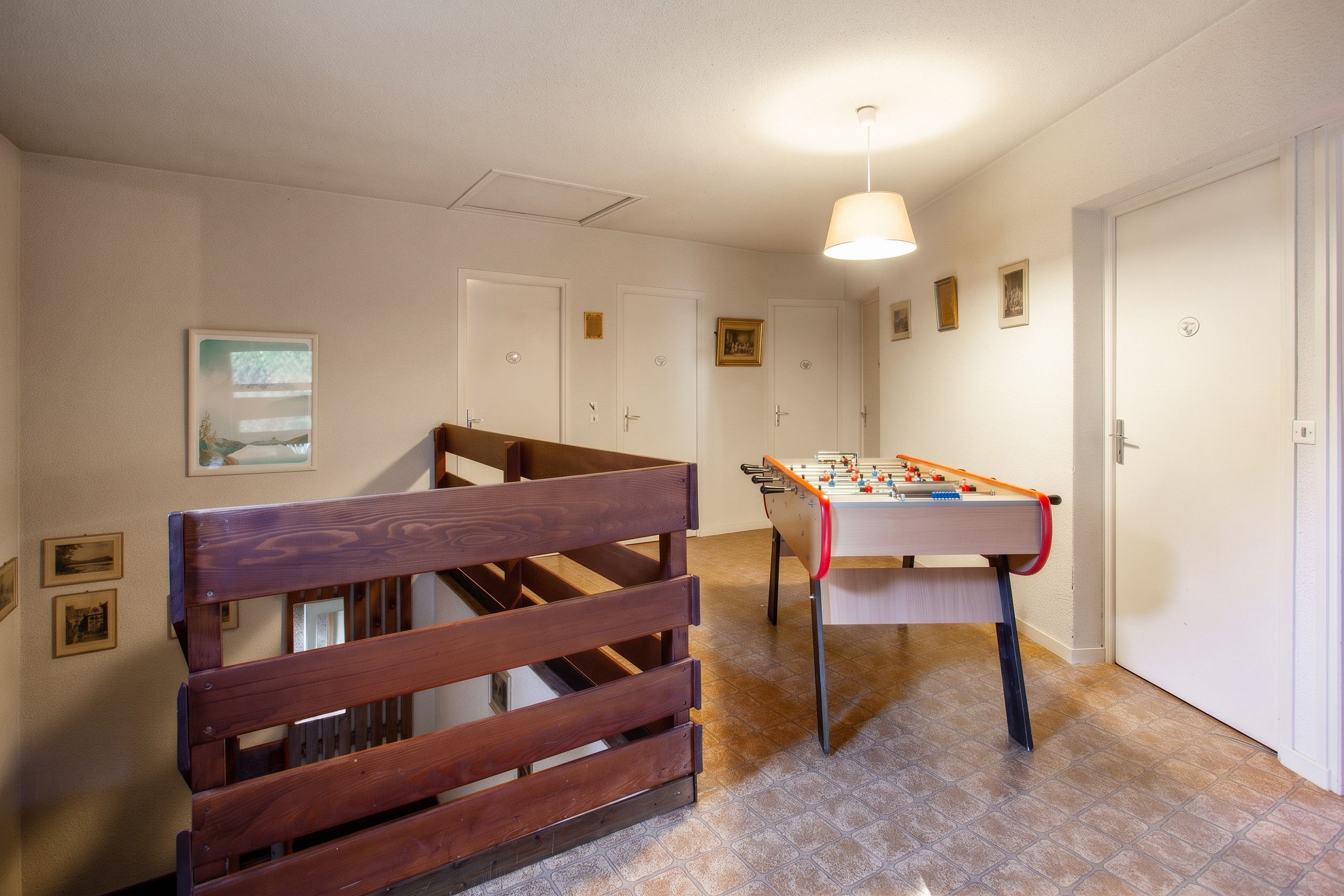 Une pièce avec un banc en bois, une table de baby-foot et un escalier.
