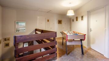 Une pièce avec un banc en bois, une table de baby-foot et un escalier.