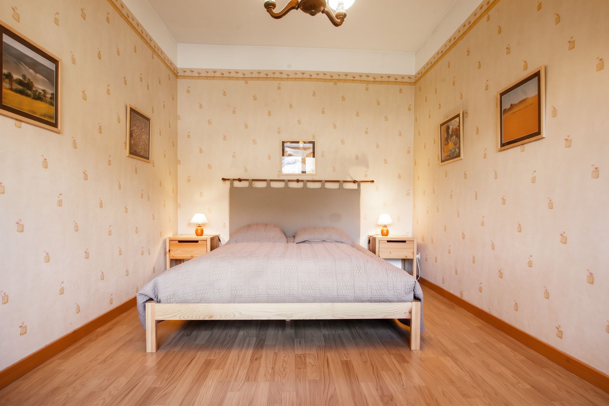 Une chambre avec un lit superposé, un plancher en bois et un papier peint à motifs.