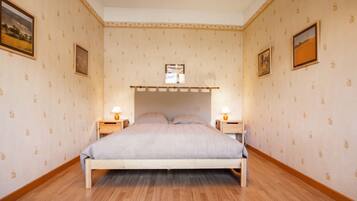 Une chambre avec un lit superposé, un plancher en bois et un papier peint à motifs.