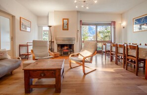 Un salon spacieux doté d’une cheminée, de meubles en bois et offrant une vue sur l’extérieur.