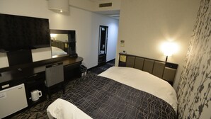 Habitación de hotel con una cama grande, un escritorio, un televisor de pantalla plana, una cafetera y un refrigerador pequeño.