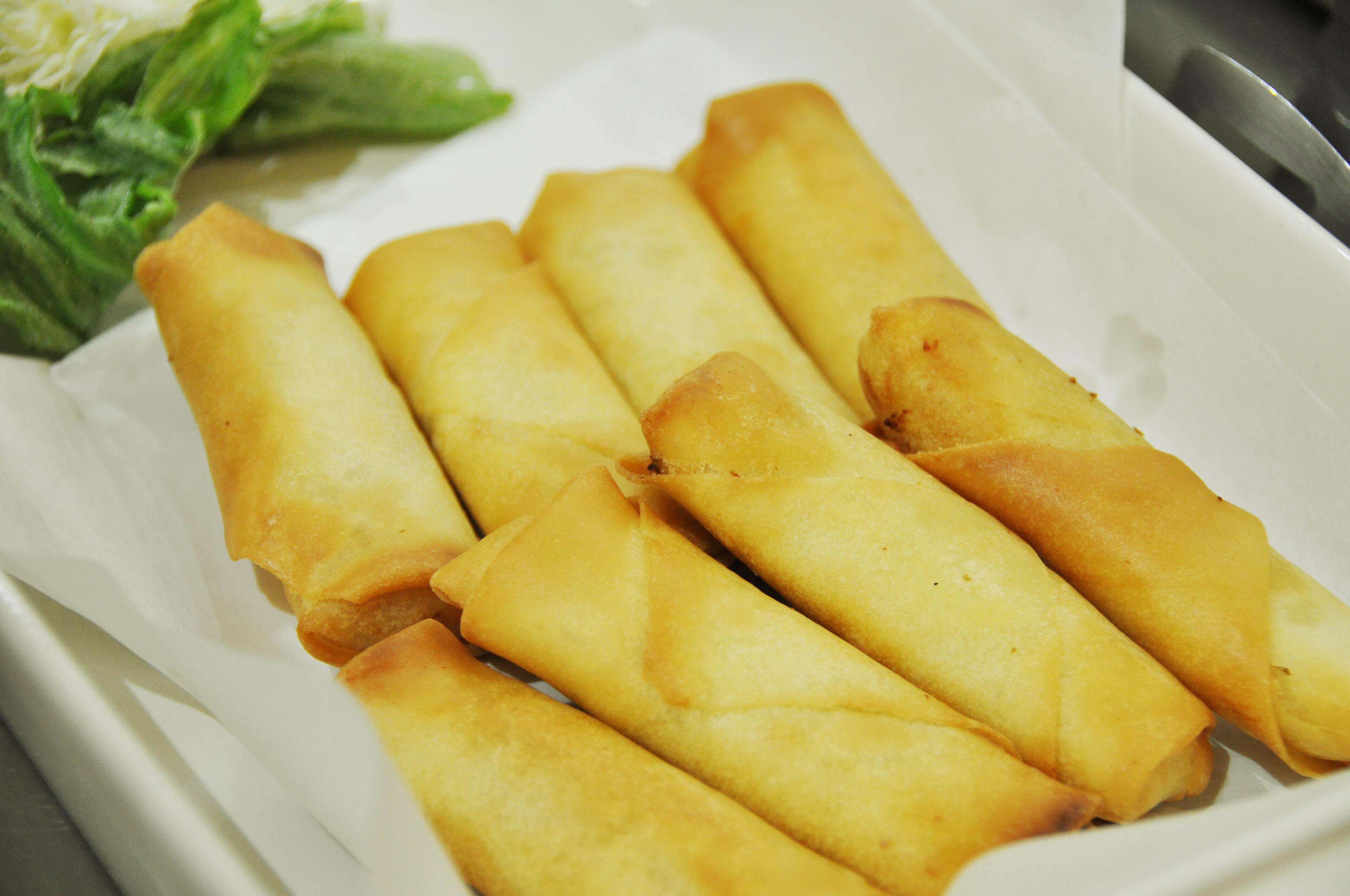 Un vassoio di involtini primavera serviti con insalata.