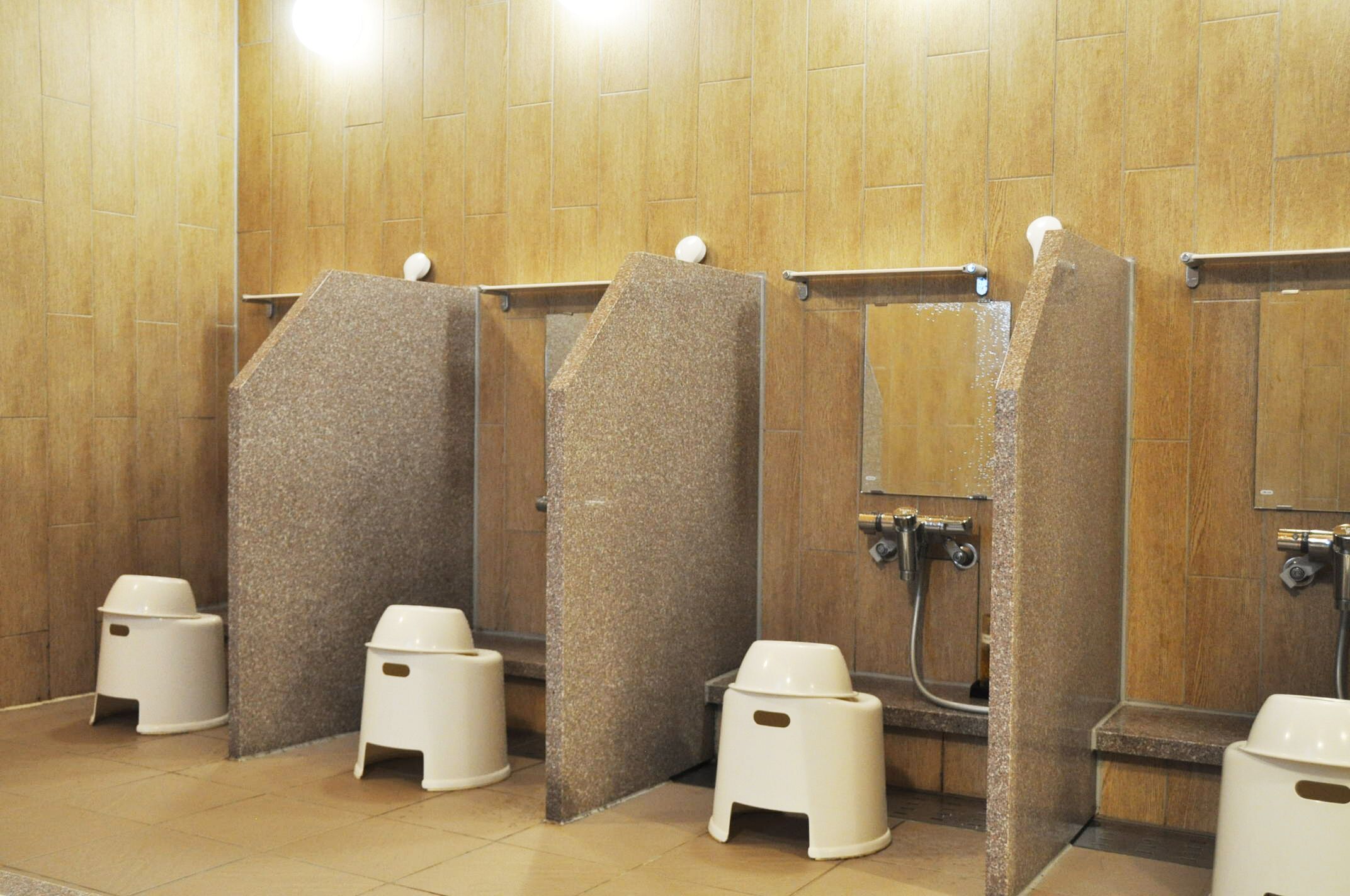 Eine öffentliche Toilette mit mehreren Kabinen, jeweils ausgestattet mit einer Toilette und einem Händetrockner.