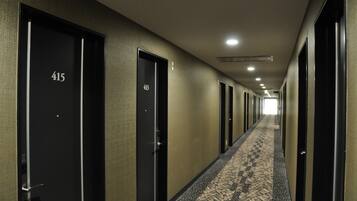 A hotel hallway with doors numbered 415 and 413, carpeted with a geometric pattern, and a ceiling with recessed lighting.
