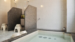 Un baño moderno con una bañera independiente, zona de ducha y un pequeño rincón de descanso con taburetes.