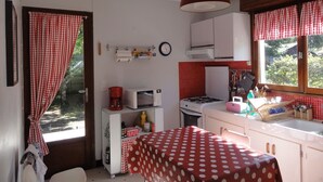 A compact kitchen with a stove, microwave, and a red and white checkered curtain. - Villa Lagoon by Agence Bru - 2433 (Lacanau)