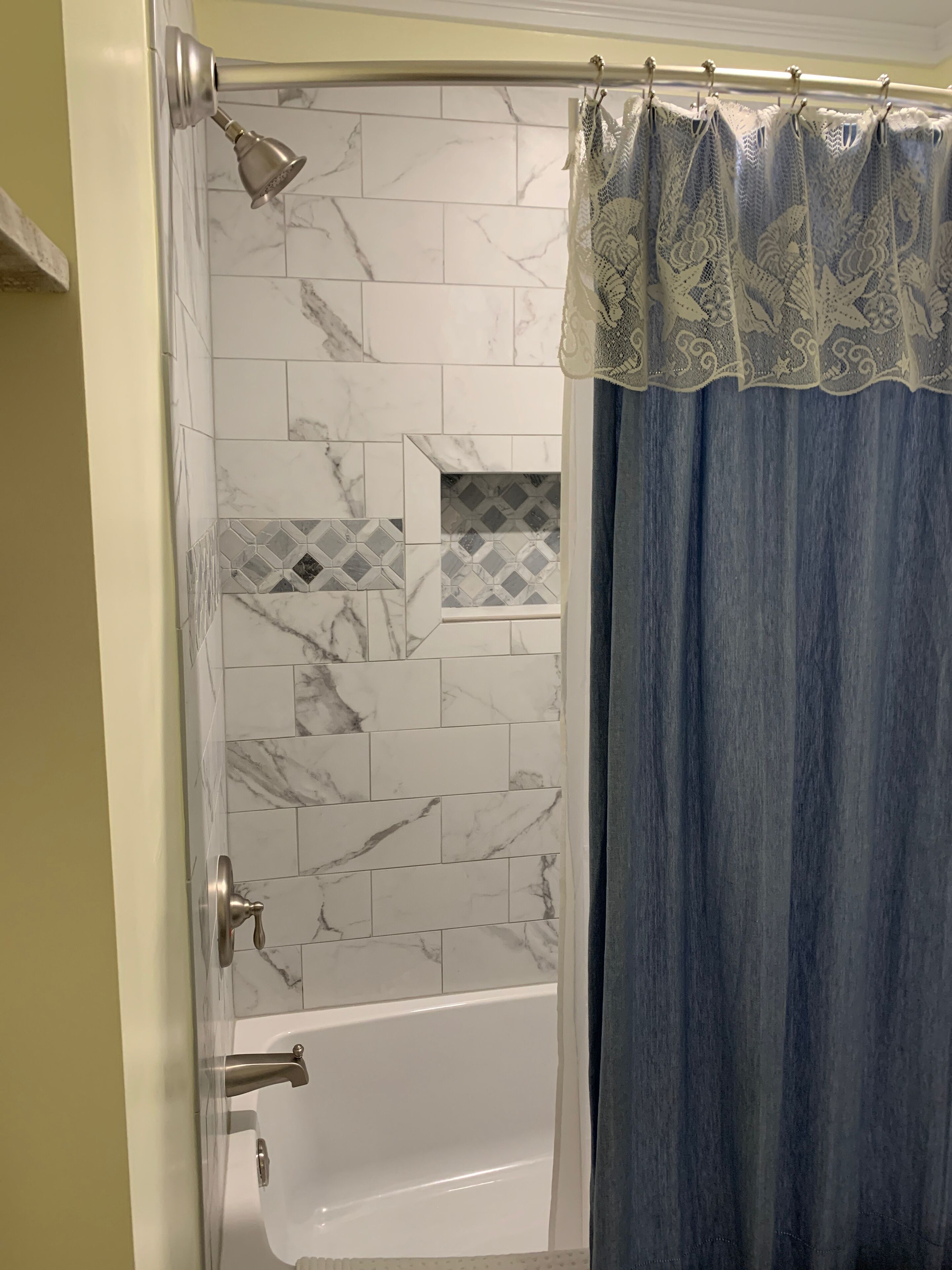 A bathroom with a bathtub, a shower, and a tiled wall with a geometric pattern.