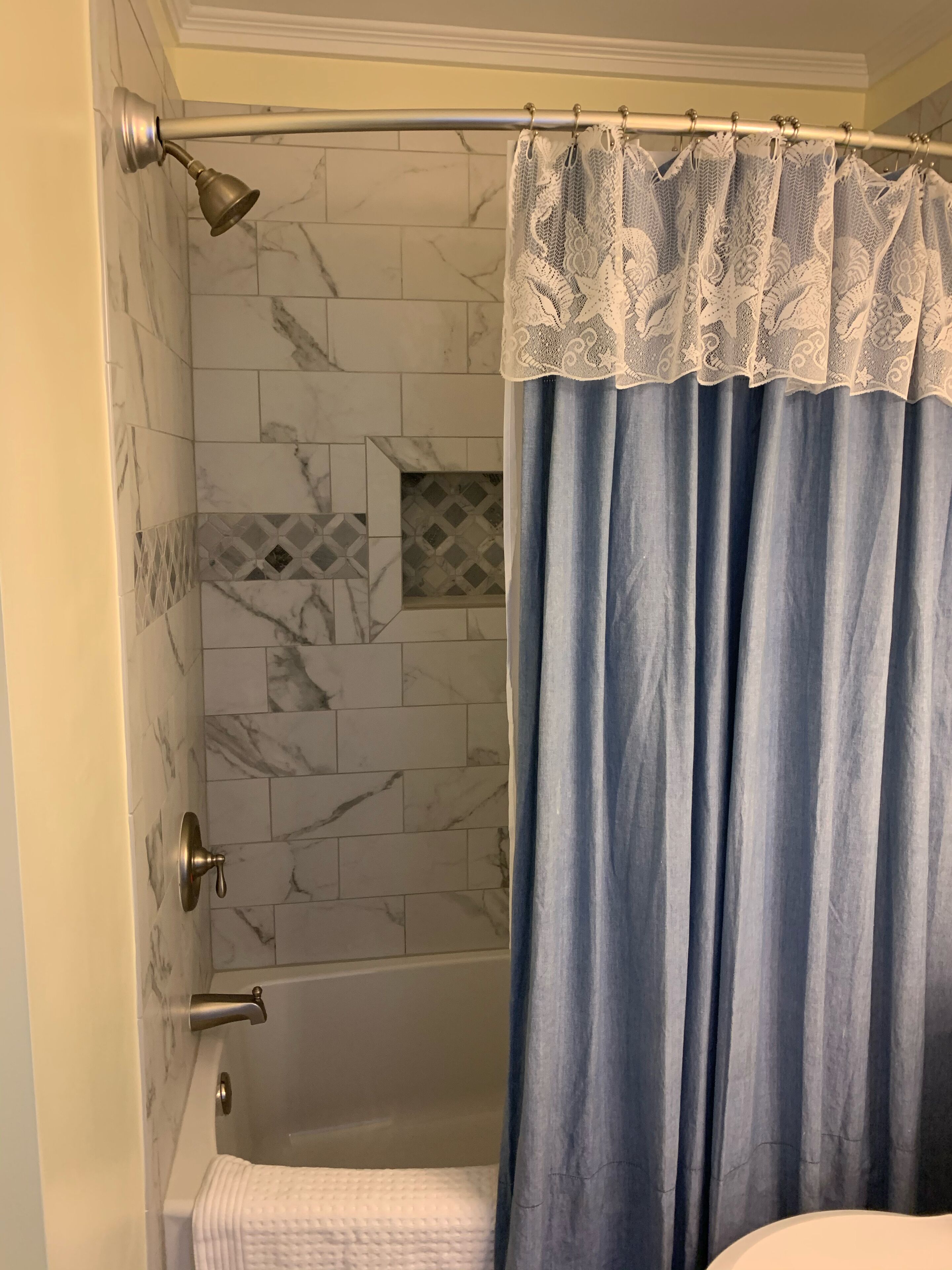 Un baño con cortina de ducha, azulejos de mármol y bañera.
