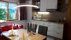 Et moderne køkken med spiseplads, en rød sofa og udsigt til grøn natur.