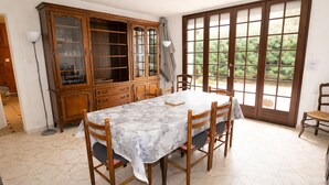 Un comedor con una mesa de mármol, sillas de madera, un aparador con puertas de cristal y un ventanal con vistas a zonas verdes.