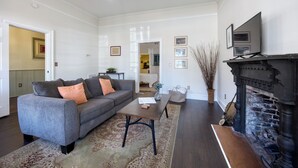 Un salon avec un canapé gris, une table basse, une cheminée et un couloir menant à une autre pièce.