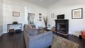 Un salon moderne avec un canapé gris, une cheminée et un téléviseur.