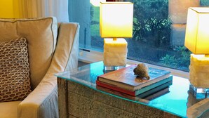 A glass-top table with a book and a decorative rock, flanked by two lamps.