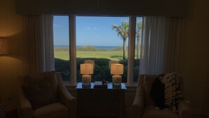 A room with two armchairs, a small table, and a view of the sea.