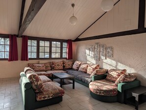 Une pièce comprenant un canapé d’angle, une table basse et une fenêtre ornée de rideaux rouges.