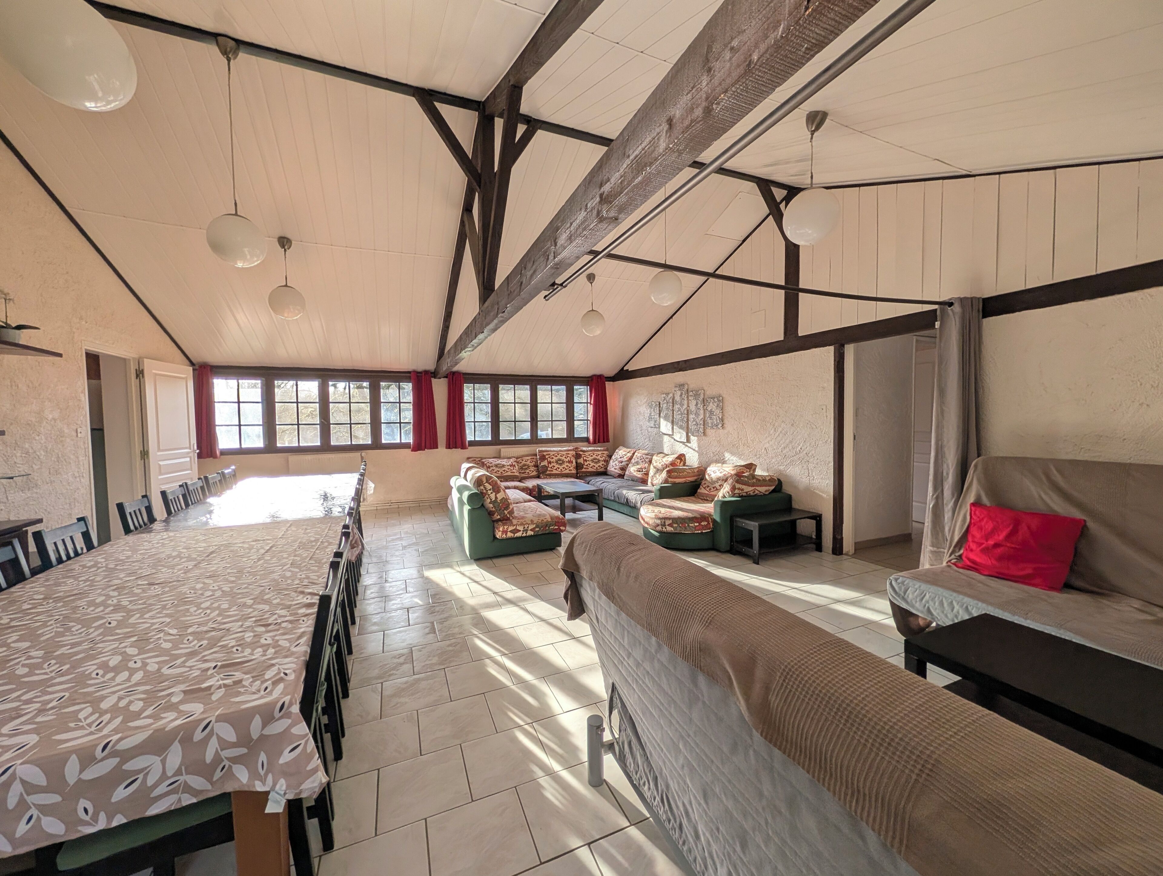 Une pièce spacieuse comprenant une longue table à manger, un ensemble de canapés et un lit.