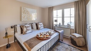 A neatly arranged bedroom with a bed, bedside table, and a window with curtains.