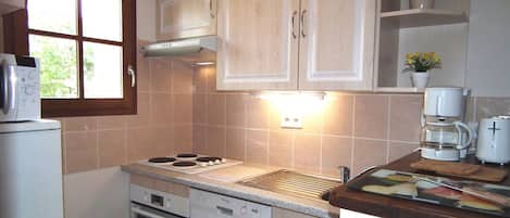 A compact kitchen with a stove, oven, dishwasher, and a window.
