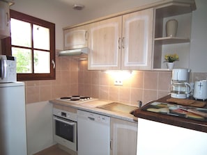 A compact kitchen with a stove, oven, dishwasher, and a window.