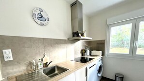 Ett modernt kök med en bänkskiva i trä, en diskho i rostfritt stål, en inbyggd tvättmaskin och en klocka på väggen.