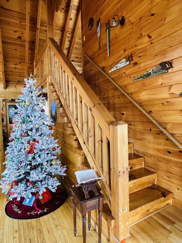 Eine Holztreppe in einer Hütte mit einem geschmückten Weihnachtsbaum.