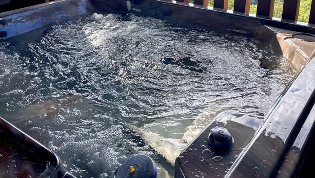Ein Whirlpool mit Holzterrasse und Blick auf eine Berglandschaft.