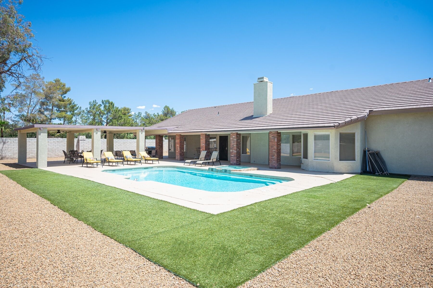 A house with a swimming pool, covered patio, and a well-maintained lawn.