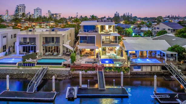 A modern residential area with multiple two-story houses, a swimming pool, and a dock with boats.