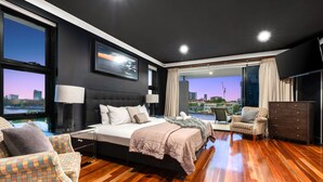 A modern bedroom with a large bed, a view of the cityscape, and a balcony with a chair.