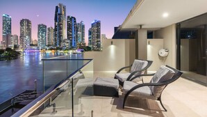 A balcony with a glass railing overlooking a cityscape at dusk.