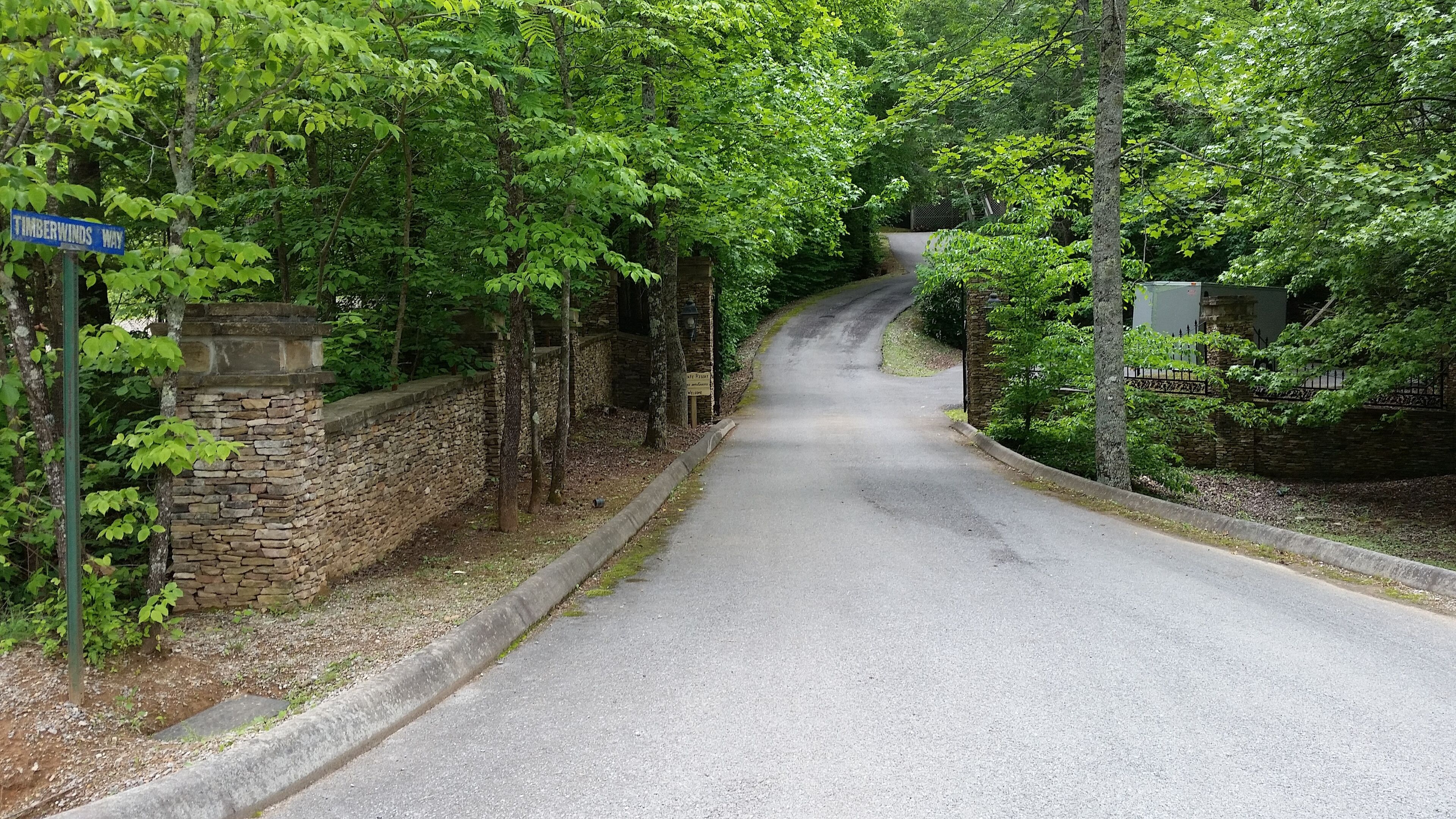 Ein schmaler Weg namens Timberwinds Way, gesäumt von Steinmauern und üppigen, grünen Bäumen.