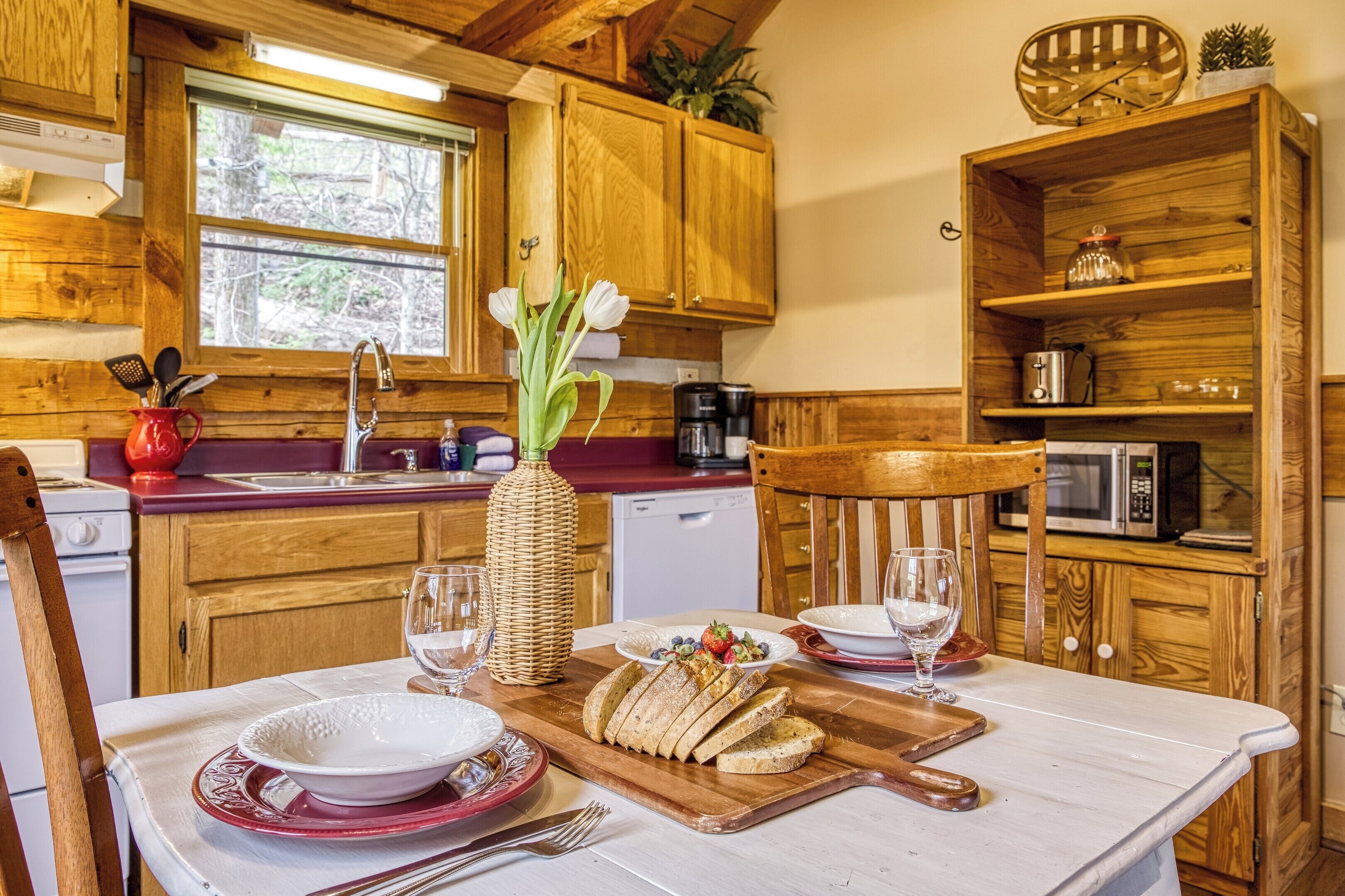 Una cocina de madera con una mesa de comedor para dos personas, un microondas y armarios de madera.
