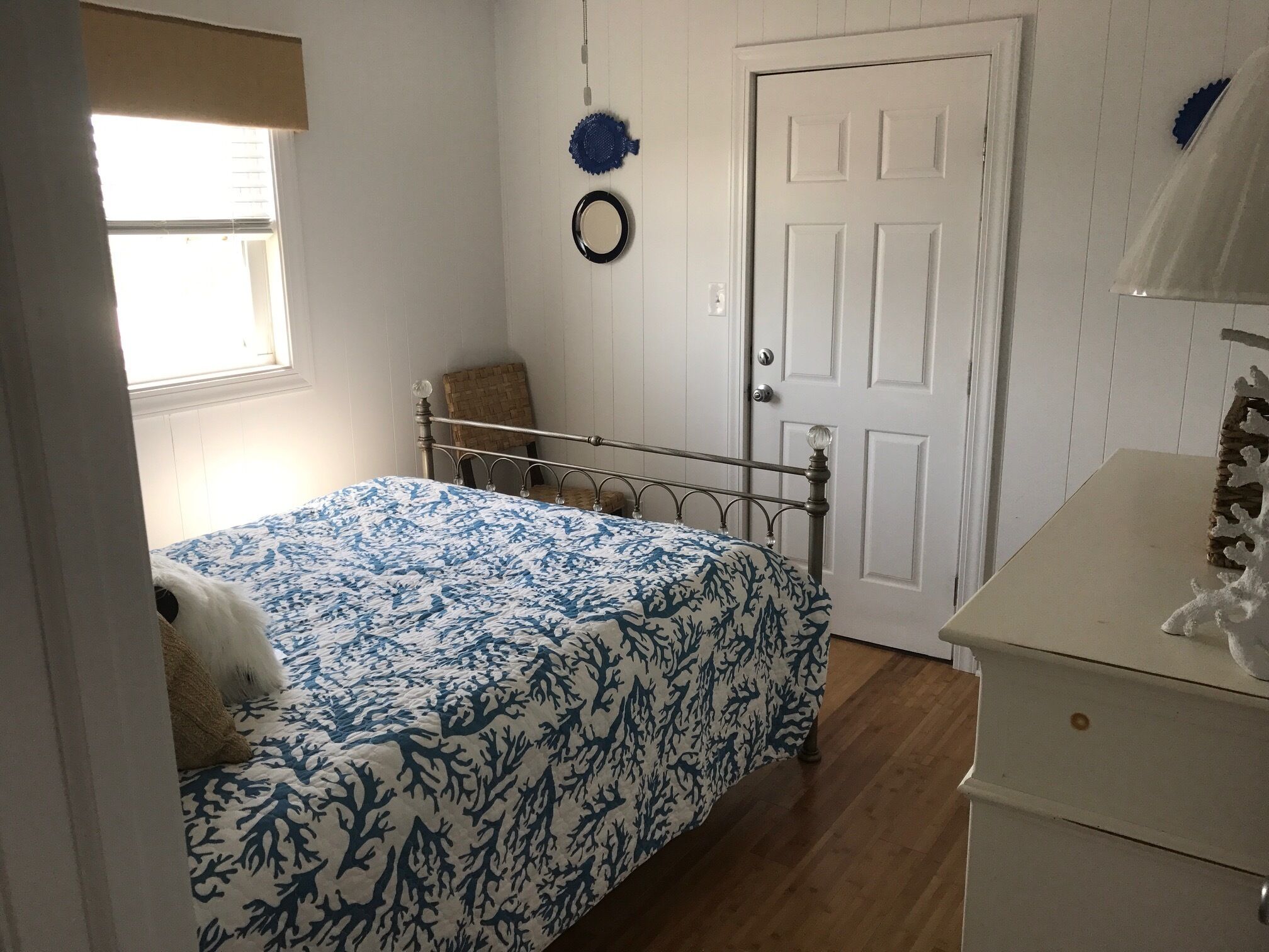 A bedroom with a bed, a dresser, a chair, a door, and a window.