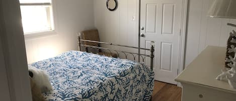 A bedroom with a bed, a dresser, a chair, a door, and a window.