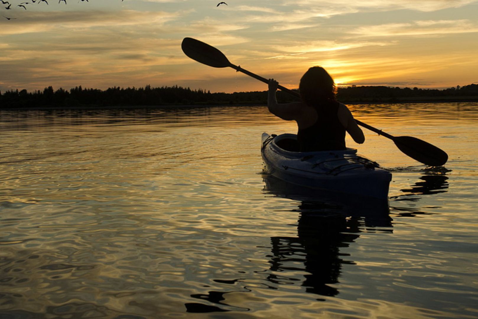 A kayak on calm water with a sunset in the background.