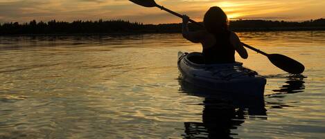 A kayak on calm water with a sunset in the background.