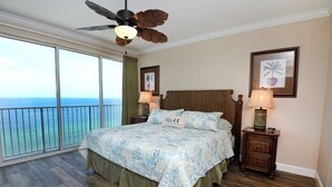 Ein Schlafzimmer mit einem großen Bett, einem Deckenventilator und Blick auf den Ozean.