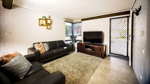 Ein modernes Wohnzimmer mit einer schwarzen Ledersofa, einem großen Flachbildfernseher und einer Holztrennelemente.