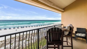 Un balcon avec vue sur la plage, des chaises et une table.