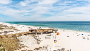 A beachside hotel with a boardwalk, beach umbrellas, and a lifeguard tower.