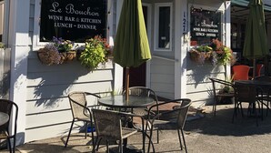 A restaurant named Le Bouchon with outdoor seating and a sign indicating it serves wine, bar, kitchen, lunch, and dinner.
