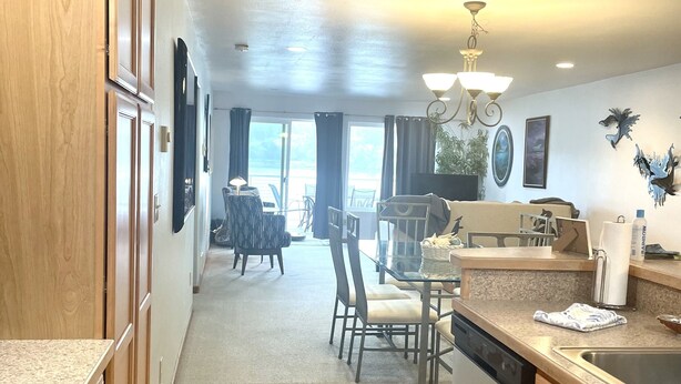 A spacious kitchen with wooden cabinets, a dining area with a table and chairs, and a view of the outdoors through large windows.